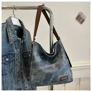 Detail of vintage denim tote bag with brown leather label and adjustable fabric strap