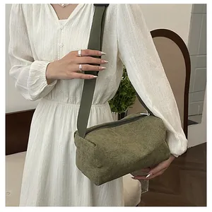Detail of army green corduroy crossbody bag texture and wide strap on model in cozy room