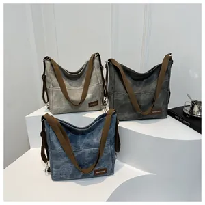 Close-up of three washed canvas tote bags in light gray, dark gray, and denim blue