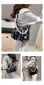 Detail of black pleated shoulder bag with large pearl chain and elegant knot strap design