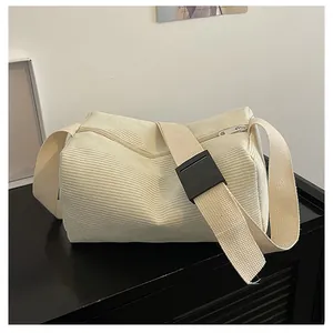 Detailed view of the creamy white corduroy fabric texture and sturdy shoulder strap buckle
