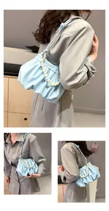 Close-up of light blue pleated cloud bag with large white pearl handle and shoulder strap