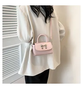 Close-up of pink mini crossbody bag with silver bow hardware and top handle detail