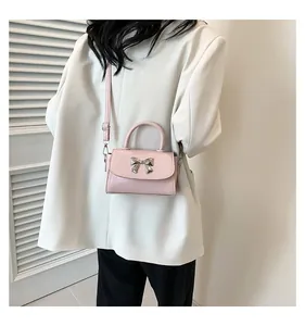 Light pink patent leather mini crossbody bag with a silver bow knot shown on a model