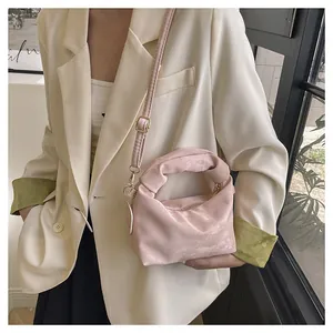 Detail of pink velvet pleated bag with golden metal hardware and a slim leather strap