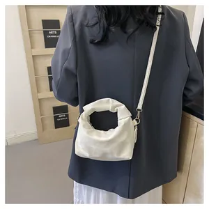 Close-up of white pleated cloud bag showing leather texture and detachable shoulder strap