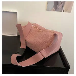 Detailed view of pink corduroy fabric texture and plastic buckle on crossbody bag strap