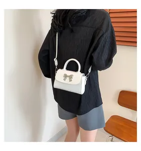 Chic white mini handbag with silver bow detail shown on a model for everyday styling