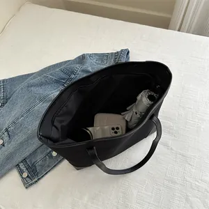 Black canvas tote bag showing spacious interior with phone, card holder and umbrella