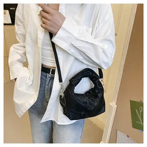 Detail of black pleated cloud bag with knotted handle and detachable shoulder strap