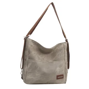 Grey canvas tote bag with front pockets and adjustable shoulder strap for casual commute