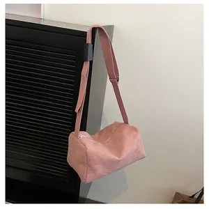 Close-up of pink corduroy texture and adjustable strap on a cylinder crossbody bag