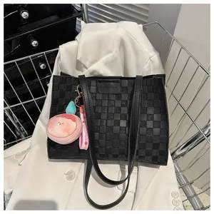 Detail of black woven texture tote bag with Fashion label and sweet charm accessory