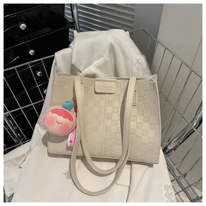 Detail showing checkered textured cream tote bag with cute pink peach plush charm