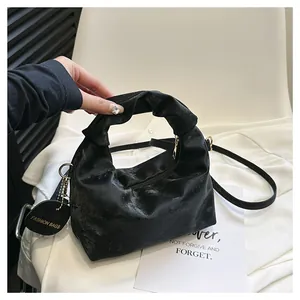 Detail of black pleated cloud bag with knotted handle, gold zipper and fashion tag