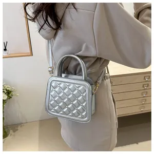 Detail of silver quilted crossbody bag with pearl accents and gold hardware on a dresser