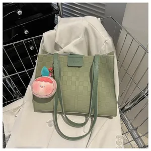 Detail of green checkered tote bag with pink peach plush charm and fashion clasp