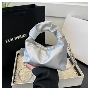 Detail of silver pleated cloud bag featuring premium metallic texture and handle