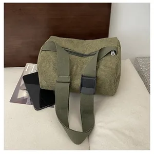 Detailed view of forest green corduroy cylindrical bag with adjustable fabric strap