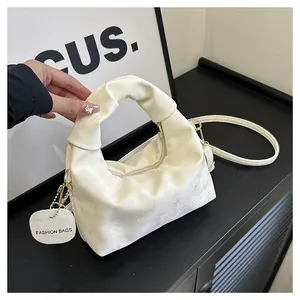 Detail of a creamy pleated cloud bag showing smooth faux leather texture and strap