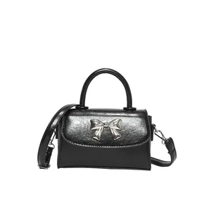 Chic black crossbody handbag with silver bow detail and textured leather finish