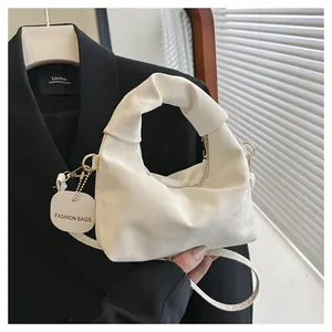 Detail of white pleated cloud bag with knotted handle and detachable gold shoulder strap