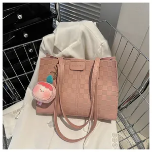 Detailed shot of pink checkered tote bag with FASHION logo and peach plush pendant charm