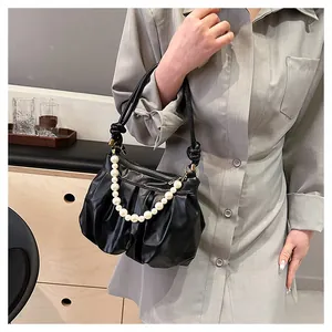 Detail of black pleated cloud bag with elegant pearl chain and knotted shoulder strap