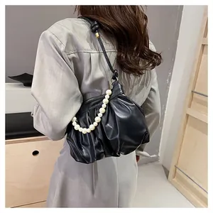 Detail of black pleated cloud bag with elegant pearl chain and knotted shoulder strap