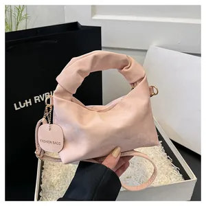 Detailed macro of a soft pink pleated dumpling bag with a gold buckle in a gift box