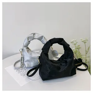 Detail view of ruched handles and velvet texture on silver and black pleated dumpling bags