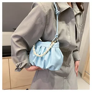 Detail of light blue pleated cloud bag with pearl chain decoration on model's shoulder