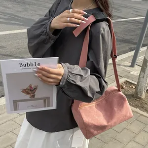 Pink corduroy crossbody pillow bag with adjustable wide strap shown in street style