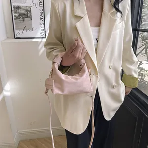 Pink pleated dumpling crossbody bag with knot handle and detachable strap on a model