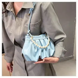 Detailed view of light blue pleated cloud bag featuring elegant pearl chain and leather strap