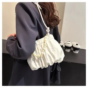 Close-up of white ruched cloud bag featuring pearl chain strap on navy blazer