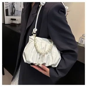 Detail of white pleated cloud bag with pearl chain handle and smooth leather texture