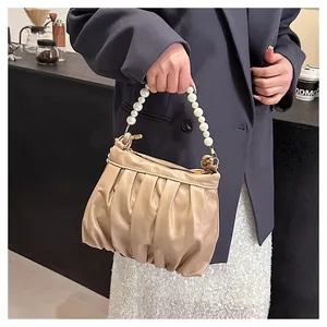 Close-up of beige ruched handbag with pearl handle on a female model in a cafe