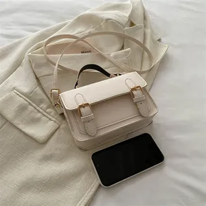 Chic cream messenger bag with retro gold buckles and adjustable strap in a clean setup