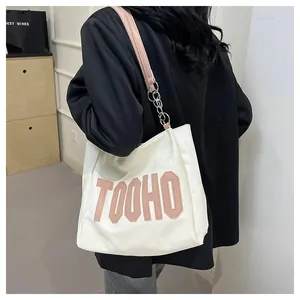 Detail of canvas tote bag with pink 3D TOOHO letters and leather chain strap