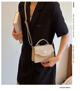 Sac à main à paillettes champagne doré avec fermoir papillon porté sur une veste de blazer