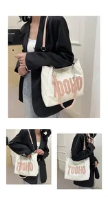 Detail view of the cream canvas tote bag with pink 3D letters and leather shoulder strap
