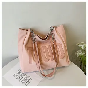 Detail of pink leather tote bag featuring TOHO lettering and silver chain strap