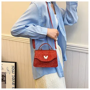 Détail du sac à paillettes rouges avec fermoir métallique en forme de papillon blanc