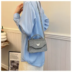 Petit sac carré pailleté argenté avec boucle papillon 3D porté en bandoulière