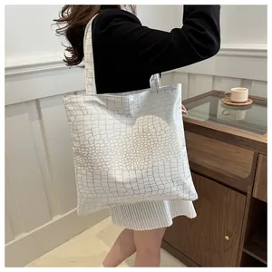 Detailed view of white crocodile pattern tote bag shown on model for daily commuting