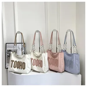 Close-up of four canvas tote bags with TOOHO lettering and metal chain straps