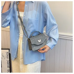 Vue détaillée du sac à bandoulière tressé argenté avec un papillon blanc en relief