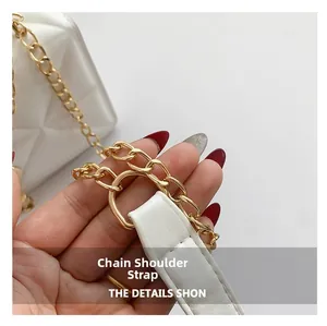 Detail of elegant gold chain shoulder strap with white leather stitching on bag