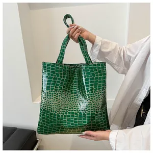 Close-up of dark green faux crocodile texture on a glossy rectangular tote bag